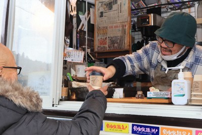 仮設住宅の住民にカップ入りのコーヒーを手渡す岩鼻伸介さん（右）＝石川県七尾市で2024年12月1日午前10時12分、奥田伸一撮影