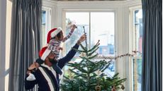 Father and daughter decorating Christmas tree in bay window at home, tradition, anticipation, childhood