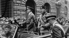 Fascism leaders, May 9, 1938: German dictator Adolf Hitler and Italian dictator Benito Mussolini standing in the back of a car, on display as they drive through Rome.