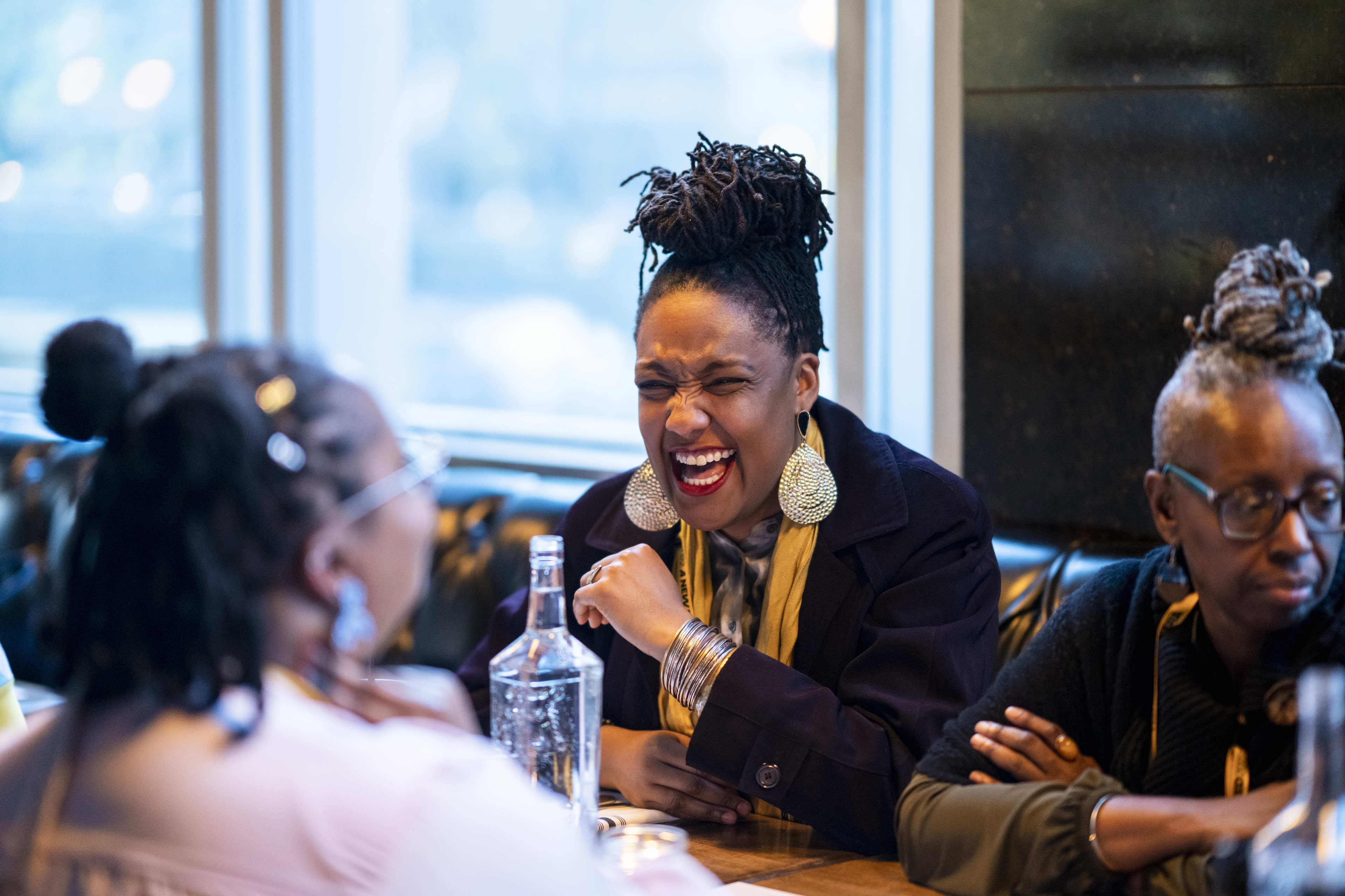 Three women laugh together during a TED Conference break.