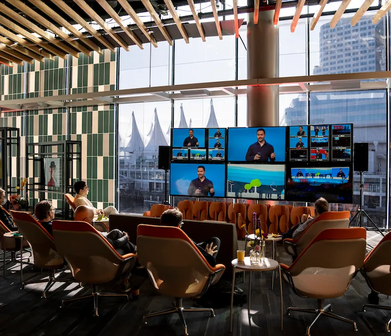 A group gathers in a simulcast space to watch various talks.