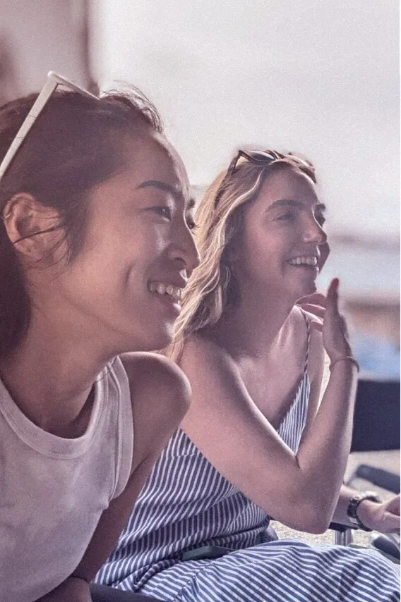 Two young women laughing while sitting on a bed