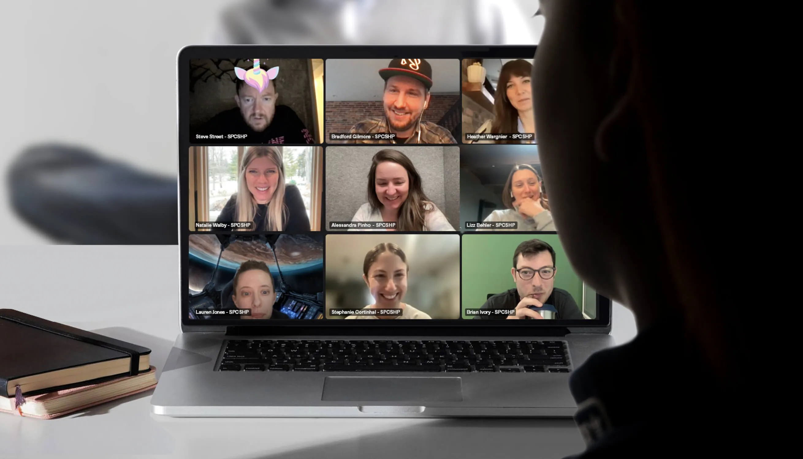 A laptop computer sitting on top of a desk with a grid of people on zoom