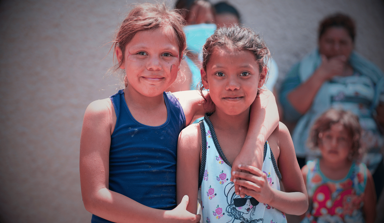 Two young Hispanic girls smile at the camera.