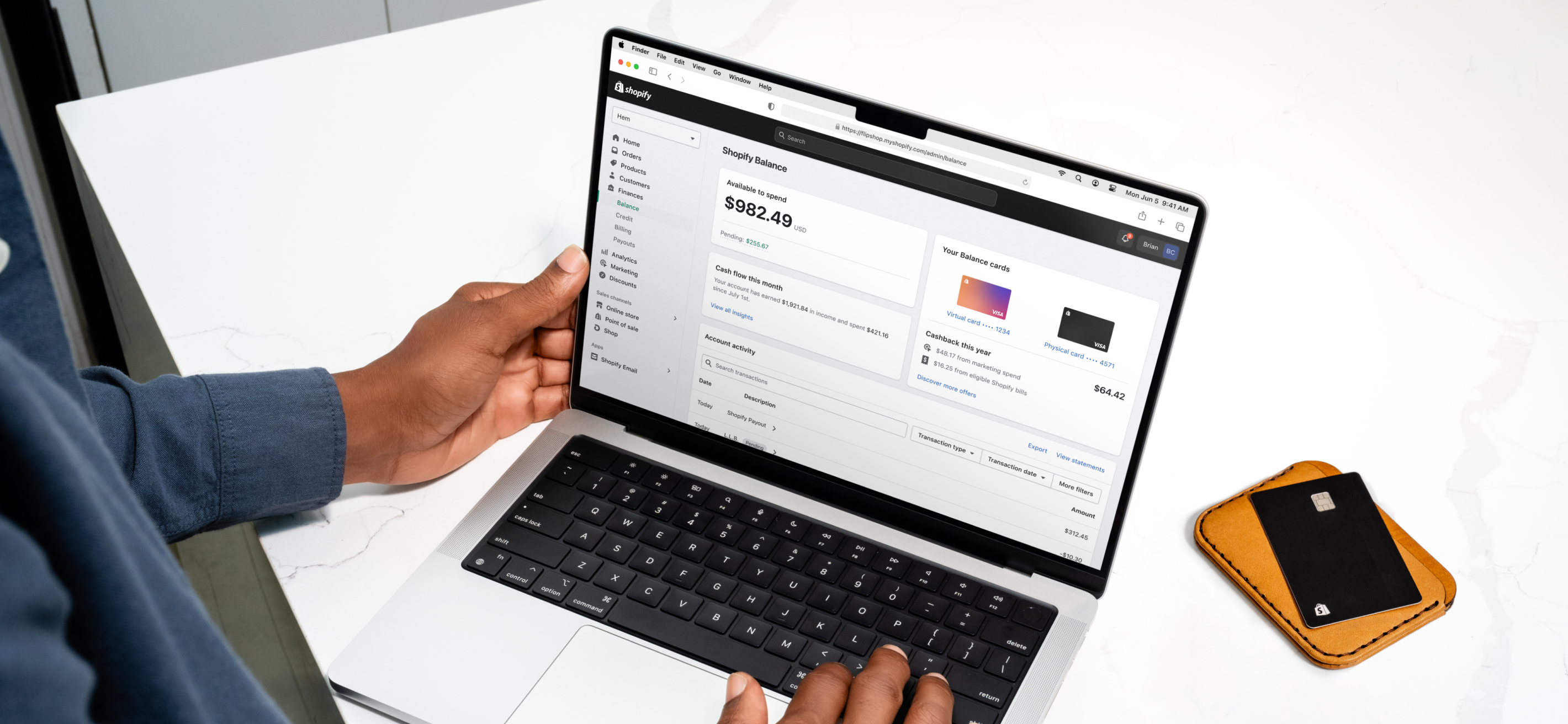 An open laptop on a white desk displays the dashboard of a merchant’s Shopify Balance account.