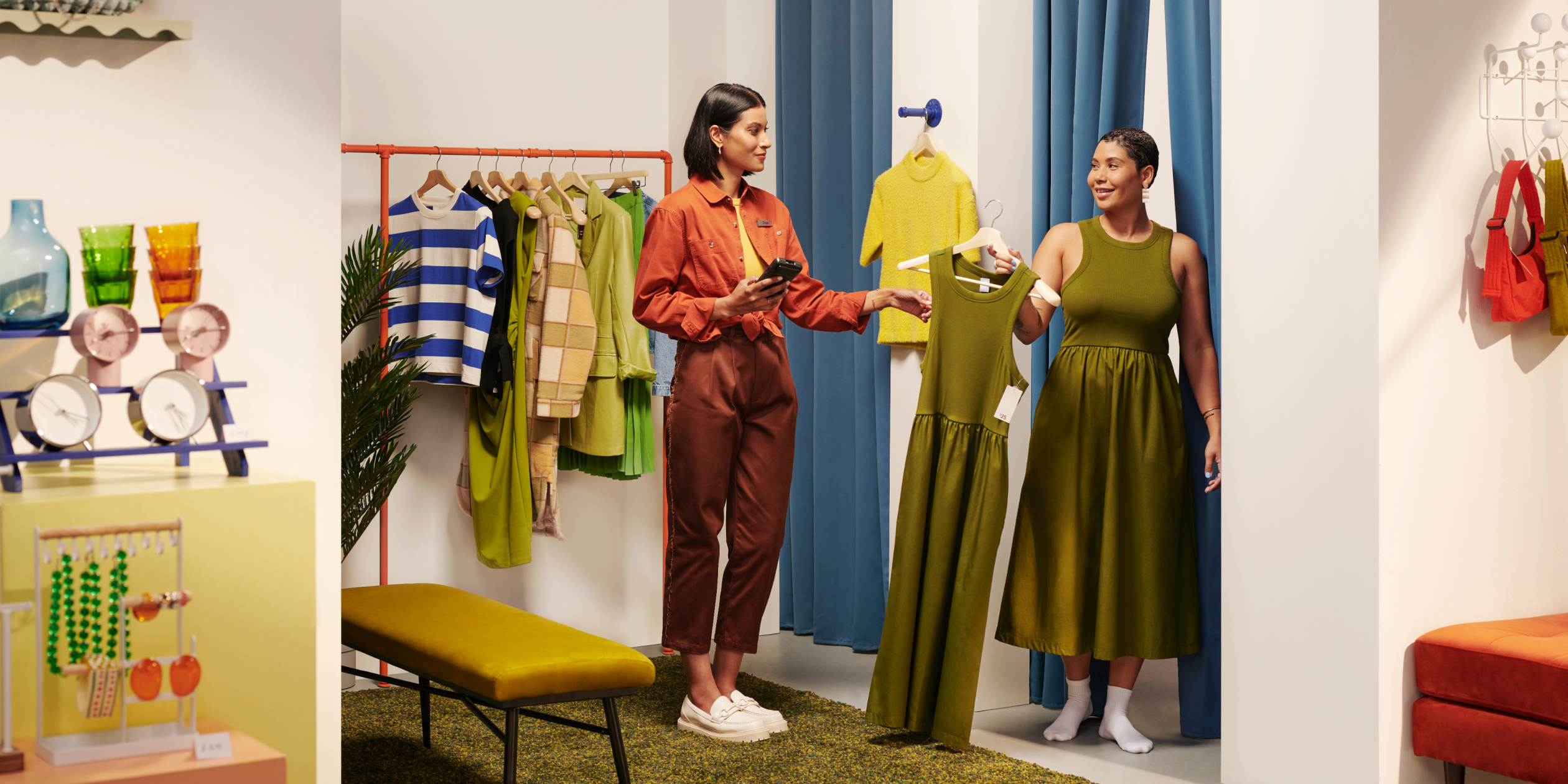 A sales associate hands a customer clothing at the dressing room, holding POS Go.