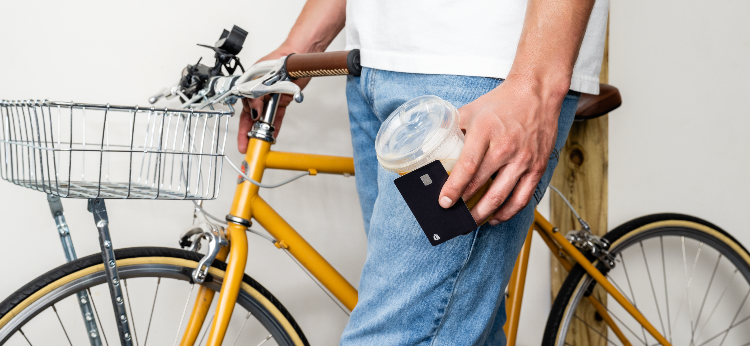 A woman with long brown hair wearing a blue shirt stands outside smiling while looking at her mobile device.