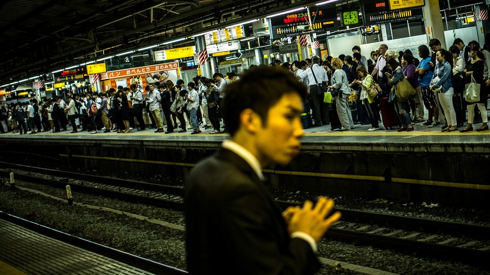 A Japanese man stands in a crowded subway station.