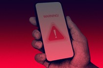 A hand holding a phone with a warning blaring on its screen