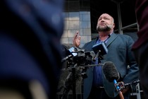 A photo of Alex Jones standing before microphones at a press conference outside a Houston courthouse