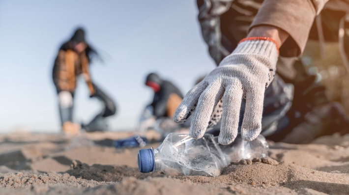 A man picks up a plastic bottle on the beach