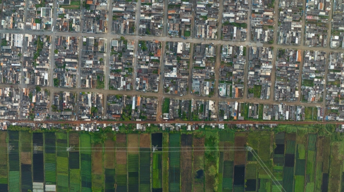 Aerial view of a peri-urban farm bordering residences and buildings in Brazil. 