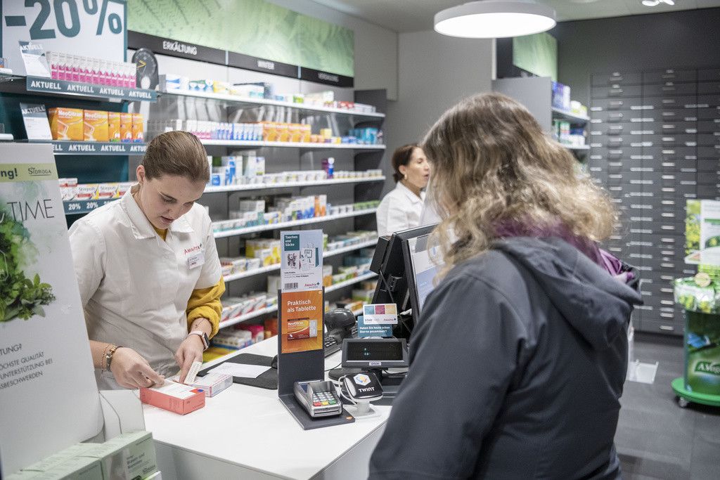 Une dame achète des médicaments dans une pharmacie.