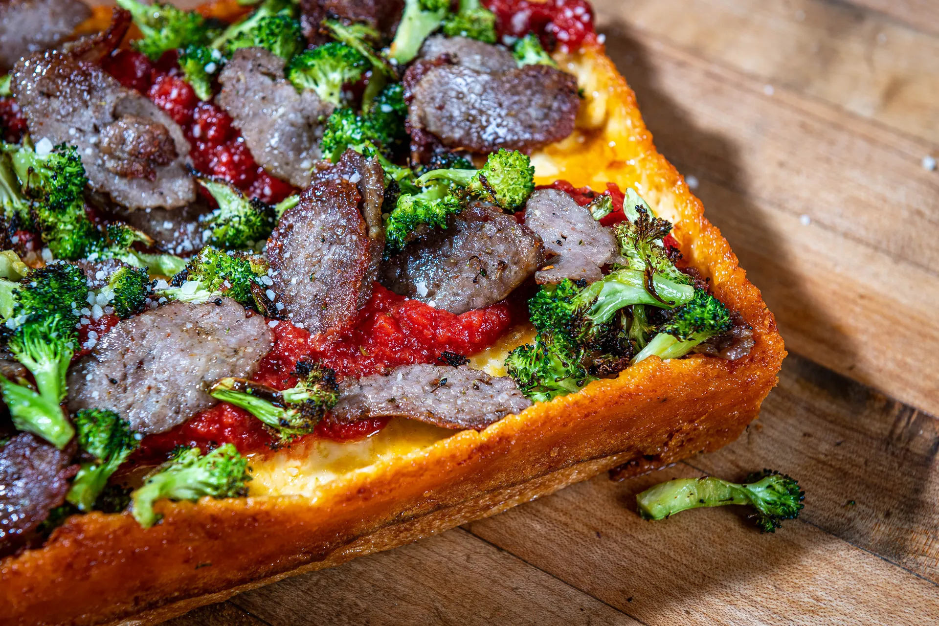 A thick pizza with vegetable toppings on a wooden table.