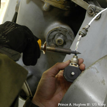 An air force engineer repairs the accelerometer on a Seahawk helicopter.