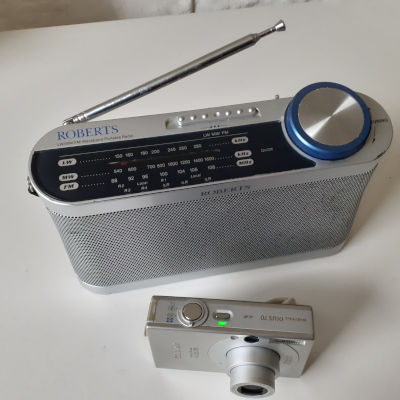 Silver-colored analog radio and digital camera.
