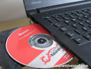 Black laptop computer loading software from an open red DVD