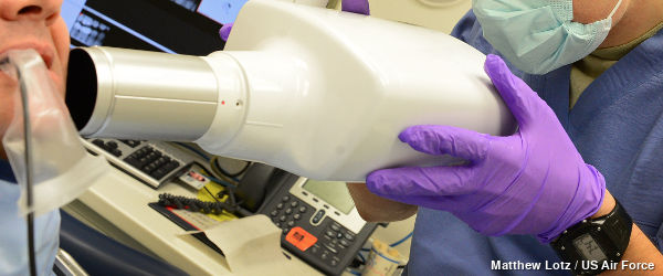 A compact dental X ray machine pressed up against a person's mouth.