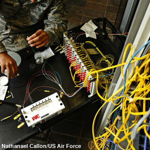 A man sitting at a table fixing yellow fiber optic cables with red connectors