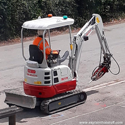 A Takeuchi mini excavator with a hydraulic concrete breaker attachment.