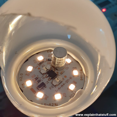 Inside the diffuser of an LED lamp, with nine LEDs lit up and a large capacitor clearly visible.