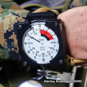 An Alti-2 MA2-30 parachute altimeter on a marine's wrist, reading 10,000ft on an analog display.