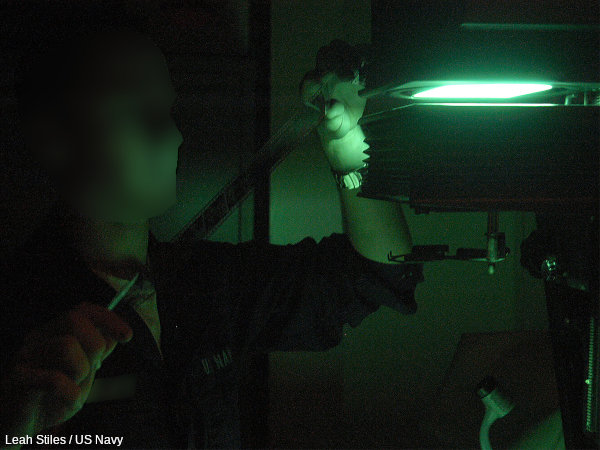 A photographic darkroom lit with green light.