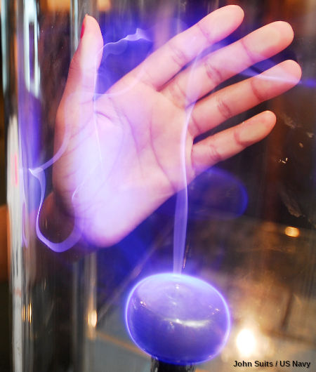 A boy playing with a plasma sphere