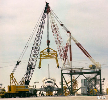 A crane derrick lifts a retired Space Shuttle