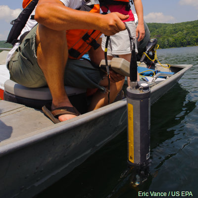 Sampling water quality over the side of a boat using a CTD sonde, including a pH meter.