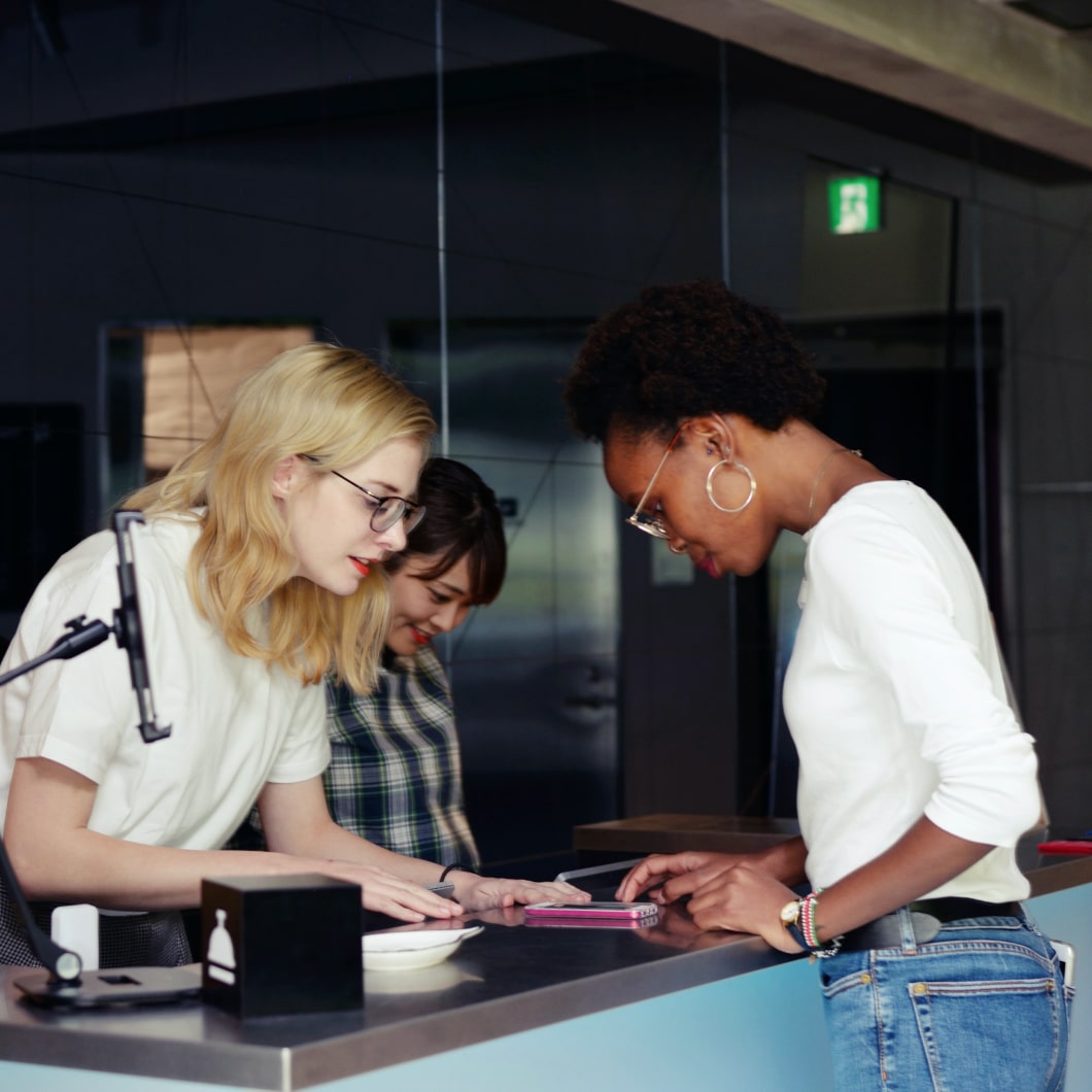 Two women at a front desk helping a new guest check in