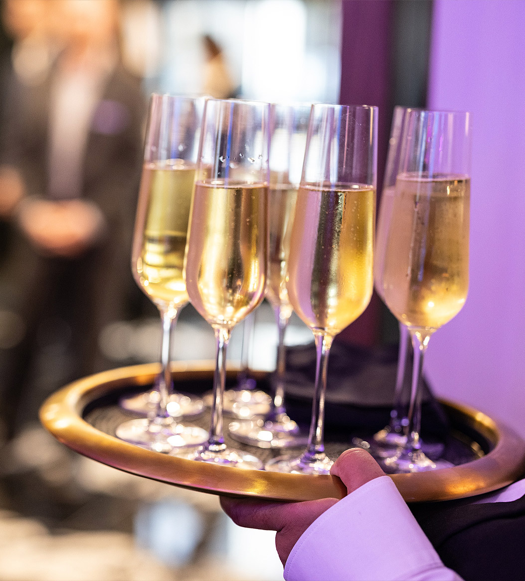 someone holding a tray of champagne flutes filled with champagne