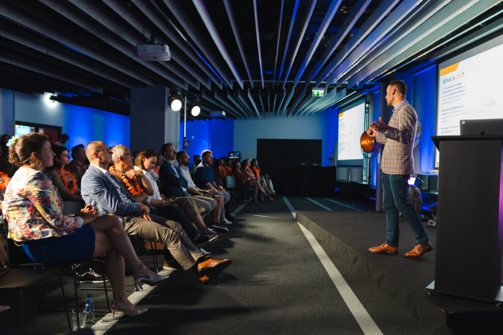 Photo of a man giving a presentation to a crowded room of people