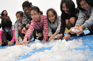 歓声を上げながら雪に触れる児童ら＝20日、久松小学校グラウンド