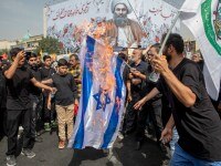 TEHRAN, IRAN - AUGUST 1: Iranians burn a representation of the Israeli flag during the funeral ceremony of Hamas leader Ismail Haniyeh and his bodyguard who were killed in an assassination blamed on Israel on Wednesday, at Enqelab-e-Eslami (Islamic Revolution) Sq. in Tehran, Iran, Thursday, Aug. 1, 2024. during a funeral procession for Ismail Haniyeh, the political leader of Hamas. Haniyeh, who had lived in Qatar, was killed in an airstrike in Tehran after attending the inauguration of Iran's new president. His body is due to return to Qatar for an official funeral and burial tomorrow. (Photo by Majid Saeedi/Getty Images) *** BESTPIX ***