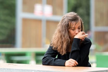 Girl sitting at a table with a look of regret