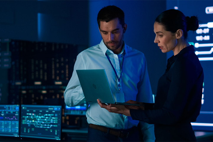 Security monitors reviewing data on laptop