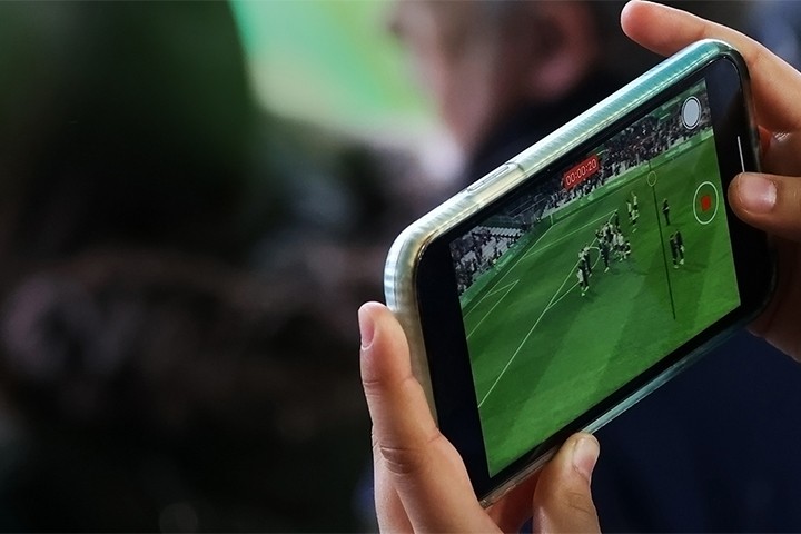 Spectator recording video on smartphone while watching a live game