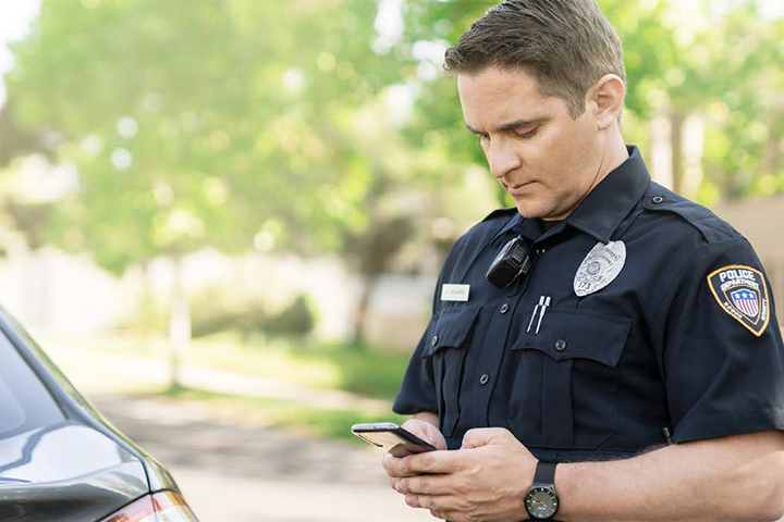 Police officer using a smartphone while standing outside