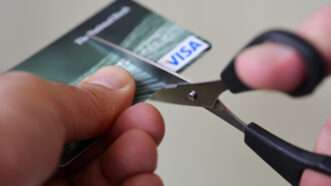 Close-up of a pair of scissors being used to cut up a Visa credit card. | Rafael Ben Ari | Dreamstime.com