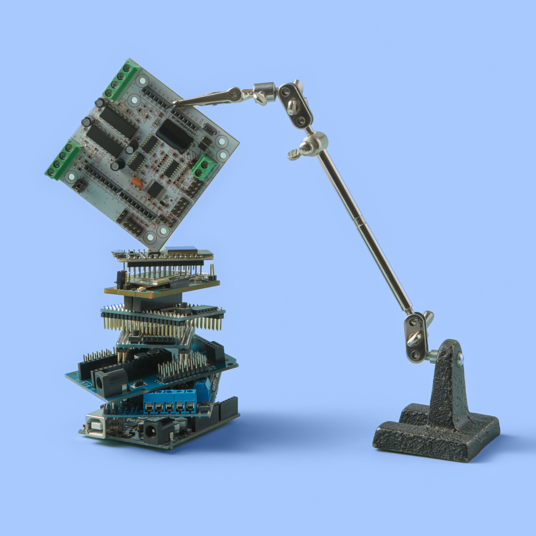 A photograph of a robotic arm creating a tower of computer chips and motherboards.