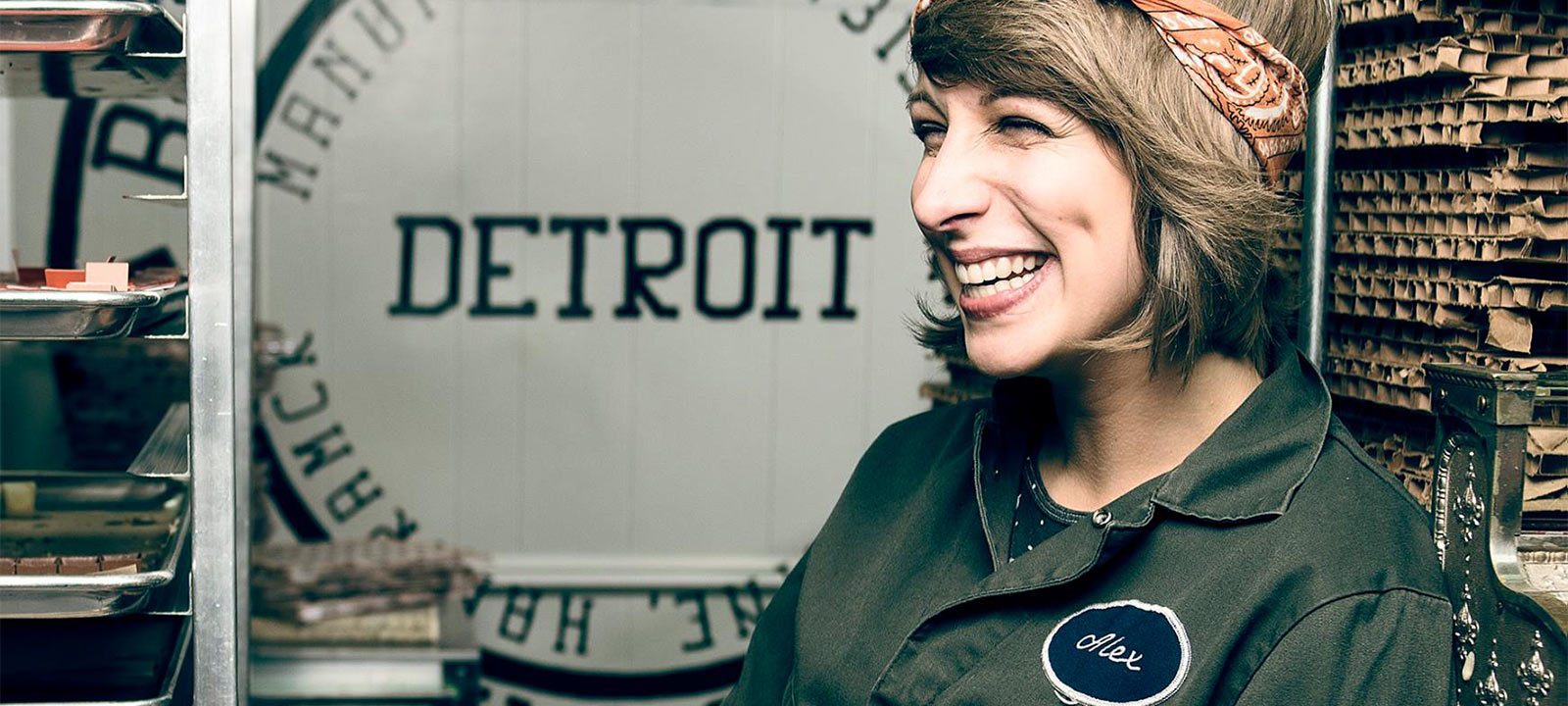 Woman smiling in front of a "Detroit" sign at our boutique hotel in Detroit