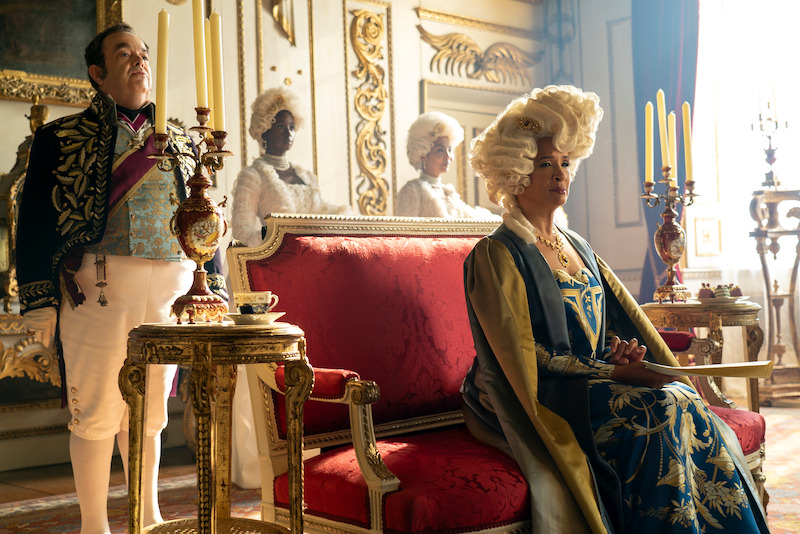 Golda Rosheuvel as Queen Charlotte sits at her throne while Hugh Sachs as Brimsley stands beside her in season 3 of 'Bridgerton'