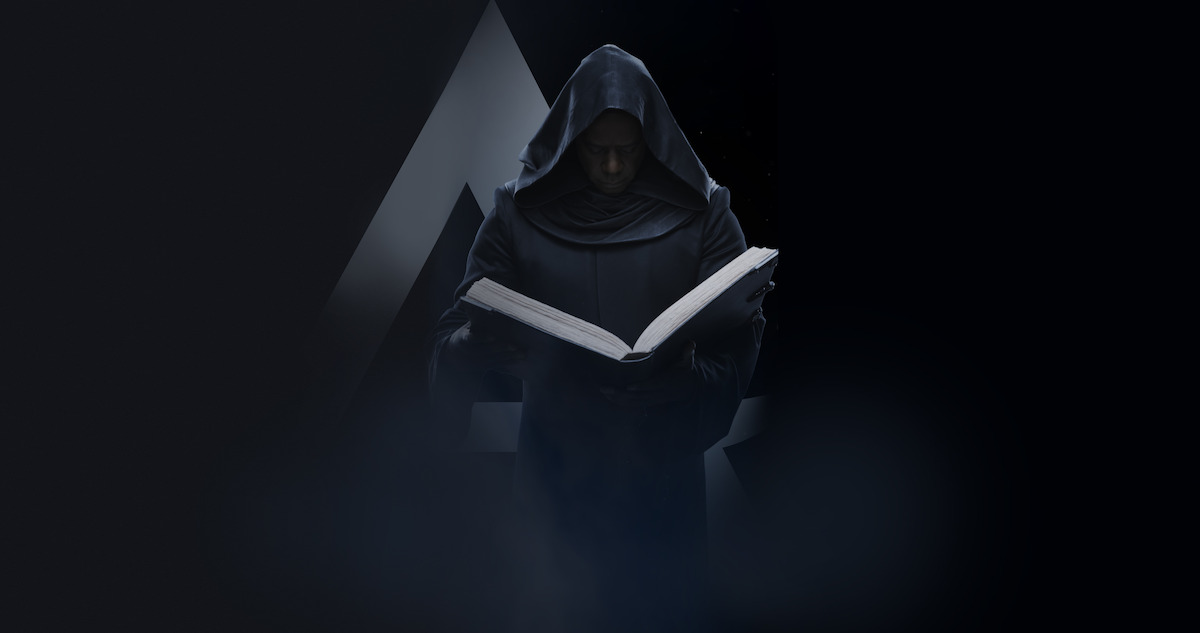 A hooded figure reading a book with a triangle in the background. 