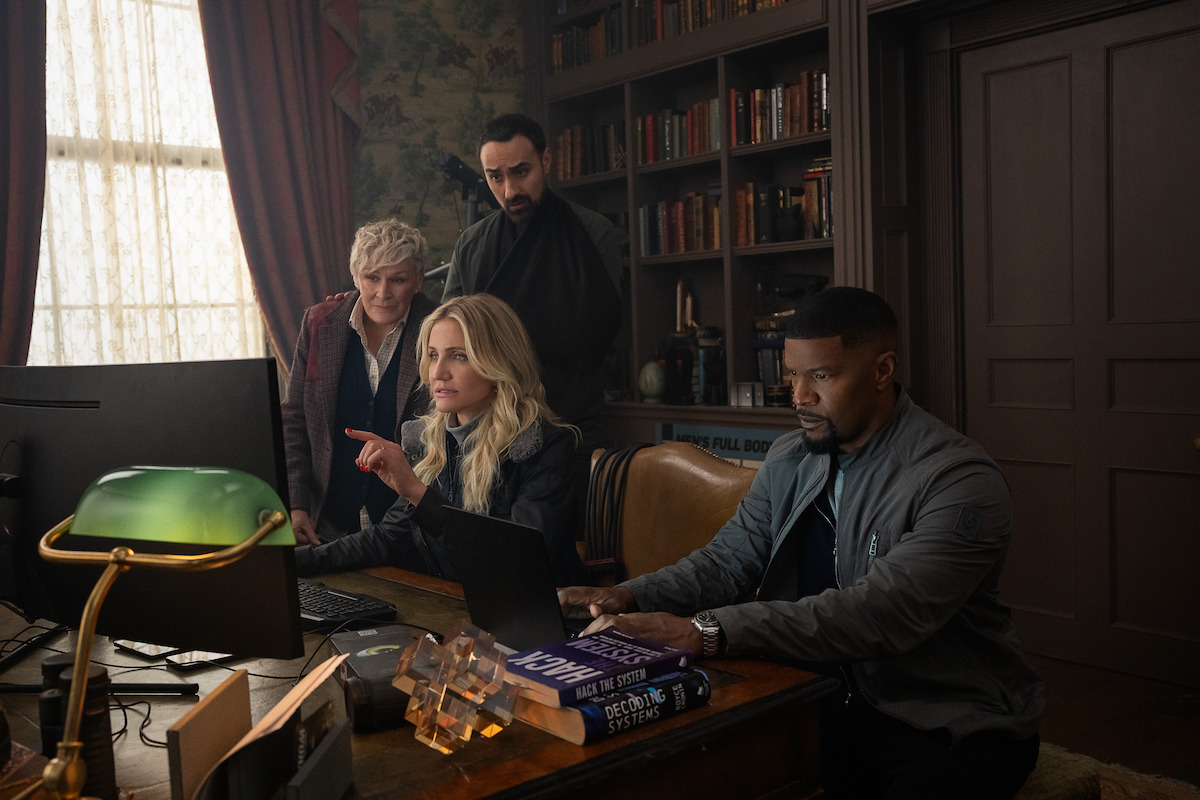 Glenn Close as Ginny, Jamie Demetriou as Nigel, Cameron Diaz as Emily, and Jamie Foxx as Matt crowd around a desk and computer in ‘Back In Action.’
