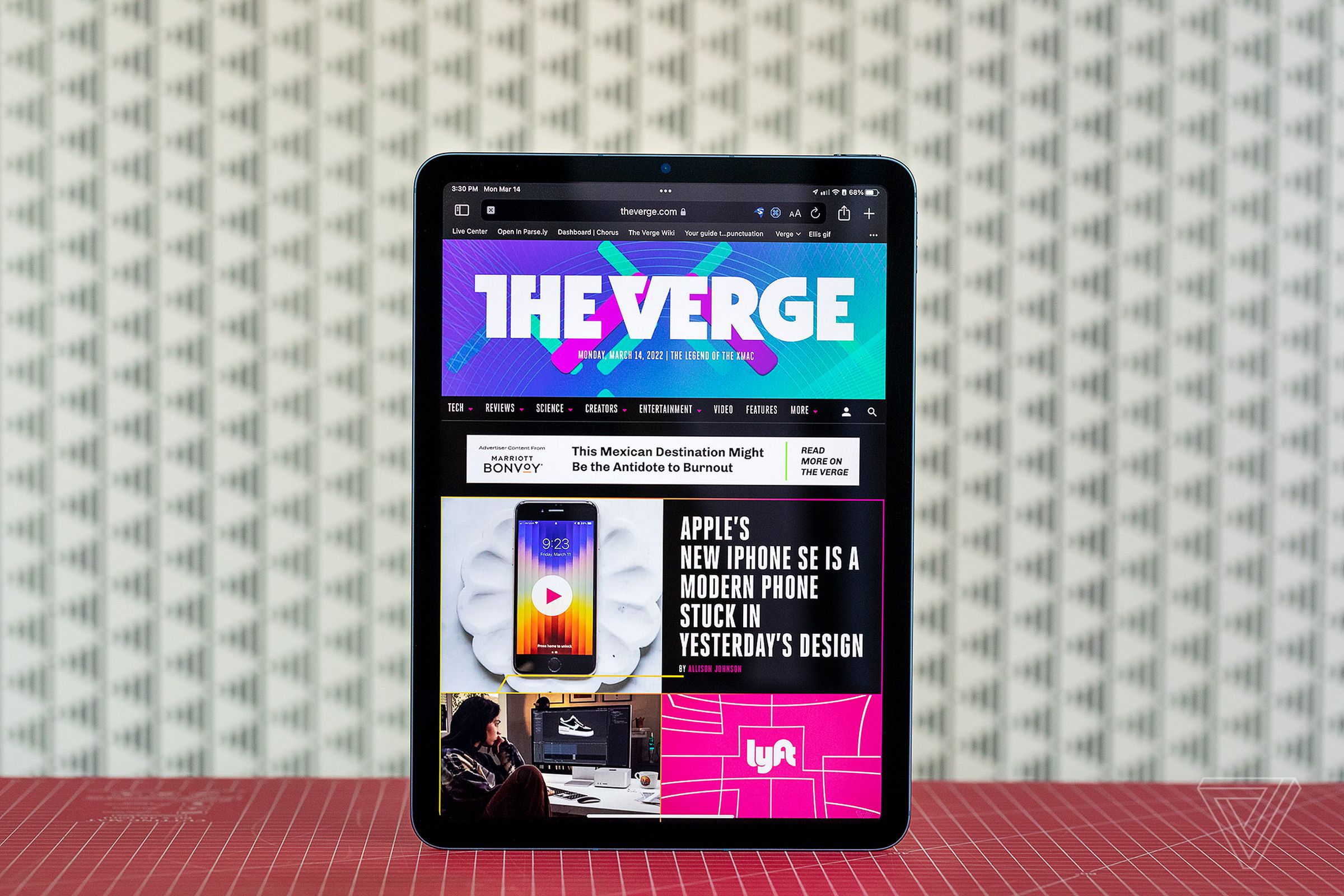 The iPad Air standing on a red table in front of a white background.