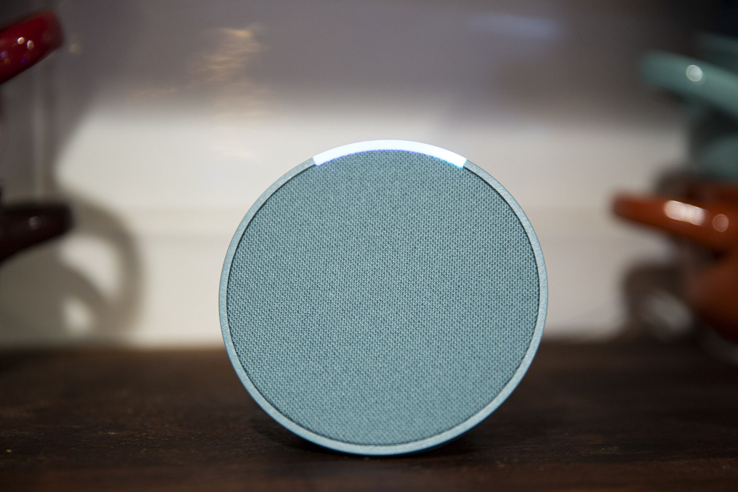 A green Echo Pop smart speaker on a countertop with its light on.