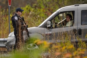 Police officers stop to question a driver at a roadblock, Thursday, Oct. 26, 2023, in Lisbon, Maine, during a manhunt for the suspect of Wednesday's mass shootings. The shootings took place at a restaurant and bowling alley in nearby Lewiston, Maine.