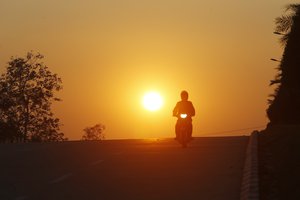 A man rides his motorcycle during sunset in Naypyitaw, Myanmar, Monday, Feb. 1, 2021