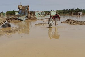 People walk after floods in Meroe, Sudan, Tuesday, Aug. 27, 2024.